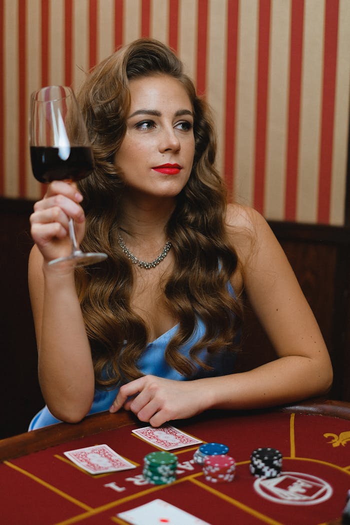 Elegant woman with wine glass at poker table, exuding glamour.